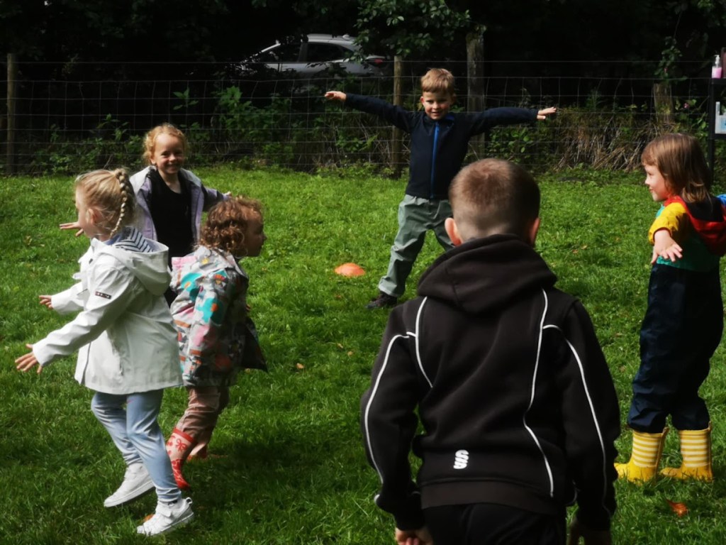 Children playing high-energy outdoor games at a birthday party, running, laughing, and participating in team challenges on a grassy field.