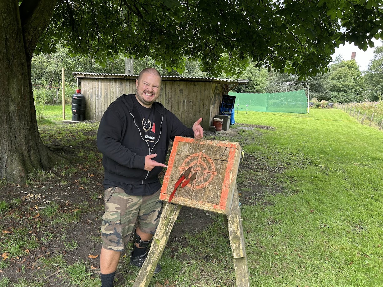 A smiling participant on the tomahawk range at Wood-Sage Outdoor after a successful throw.