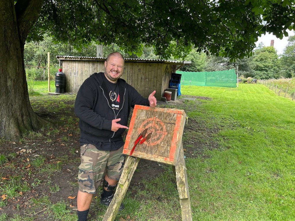 A smiling participant on the tomahawk range at Wood-Sage Outdoor after a successful throw.