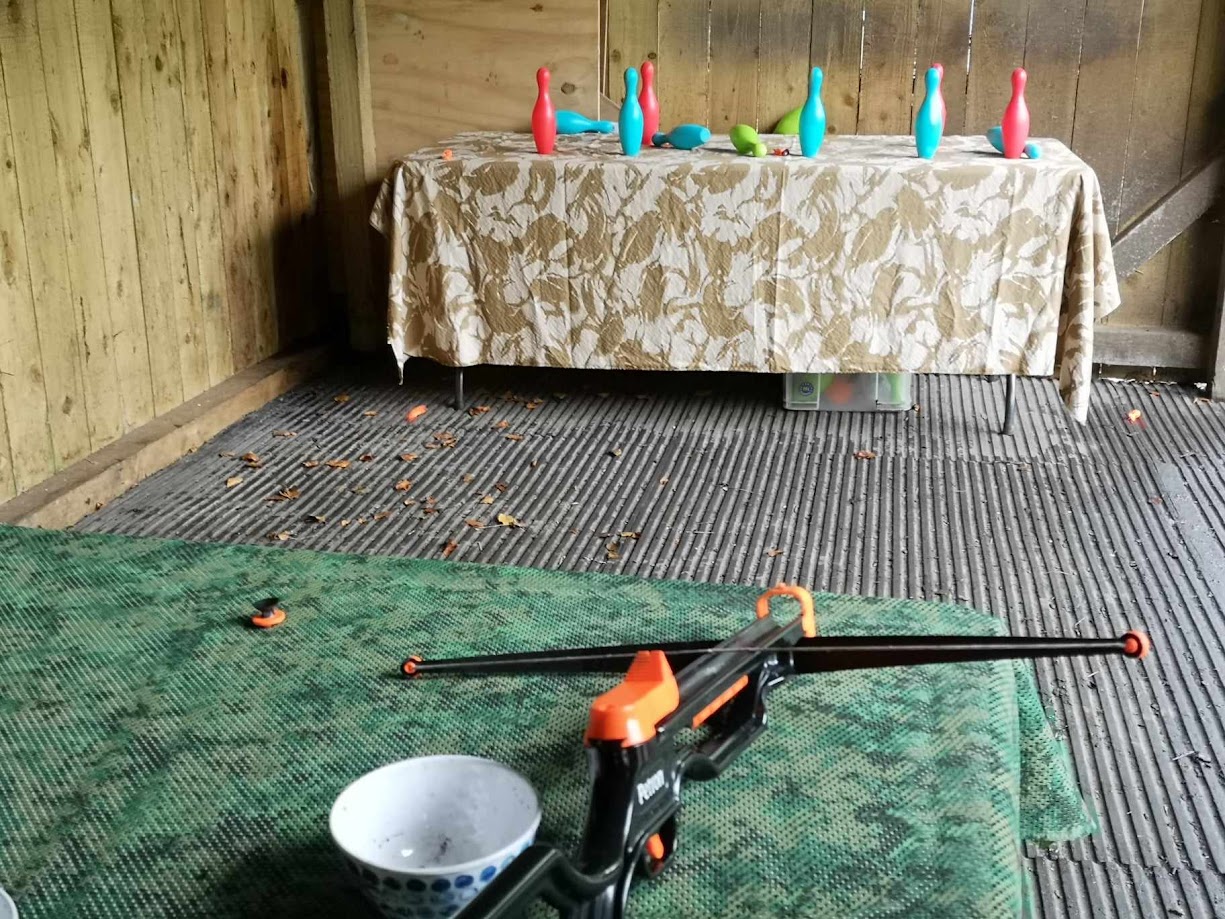A toy crossbow at a colourful target during a supervised kids' activity session, with sucker darts.