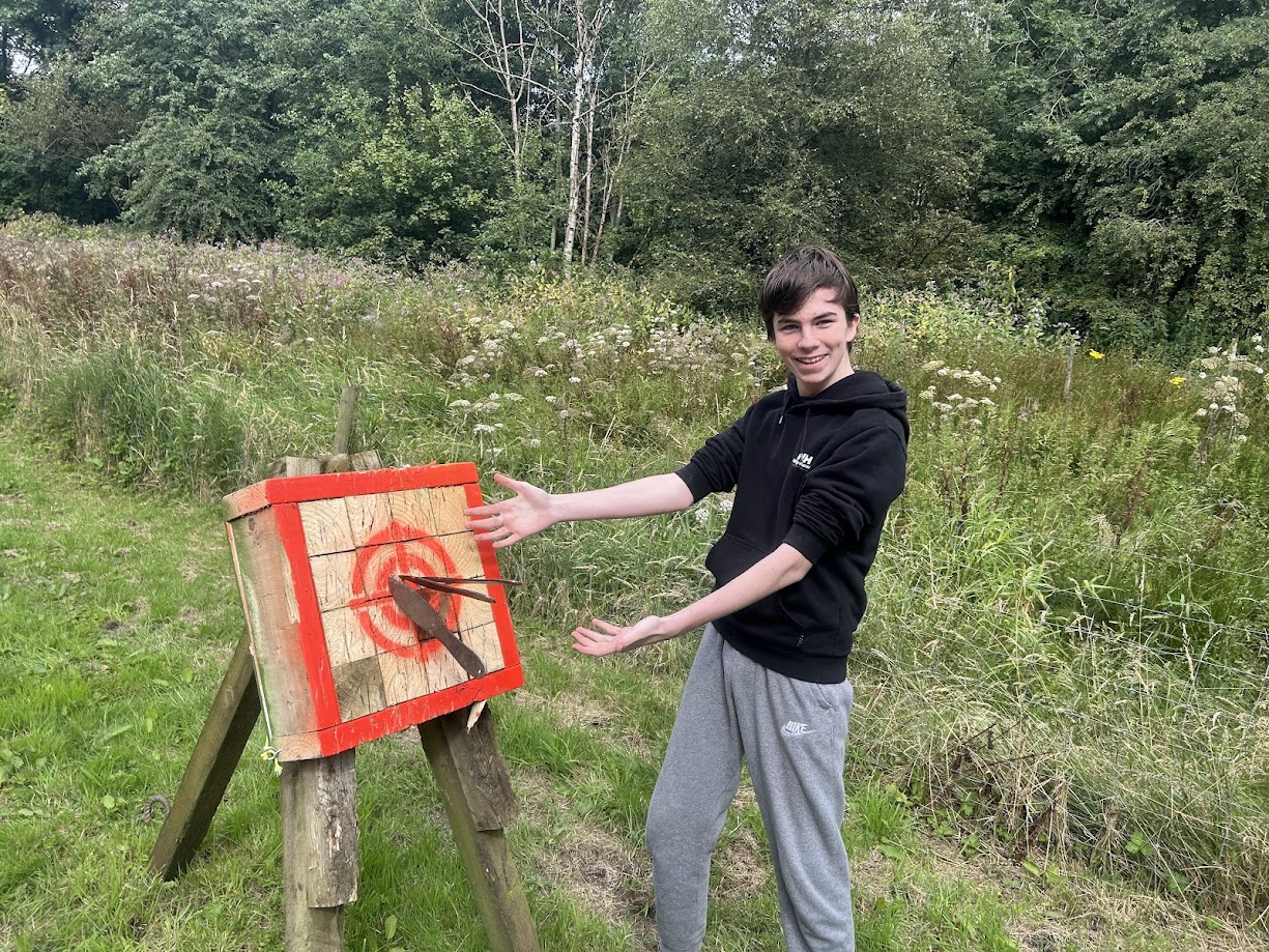 A smiling participant on the tomahawk range at Wood-Sage Outdoor after a successful throw.
