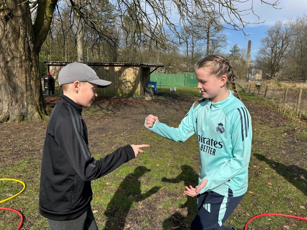 Children playing high-energy outdoor games at a birthday party, running, laughing, and participating in team challenges on a grassy field.