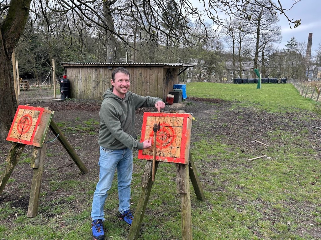A smiling participant on the tomahawk range at Wood-Sage Outdoor after a successful throw.