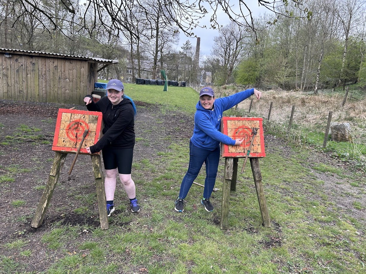 A pair of smiling participants on the tomahawk range at Wood-Sage Outdoor after a successful throw.