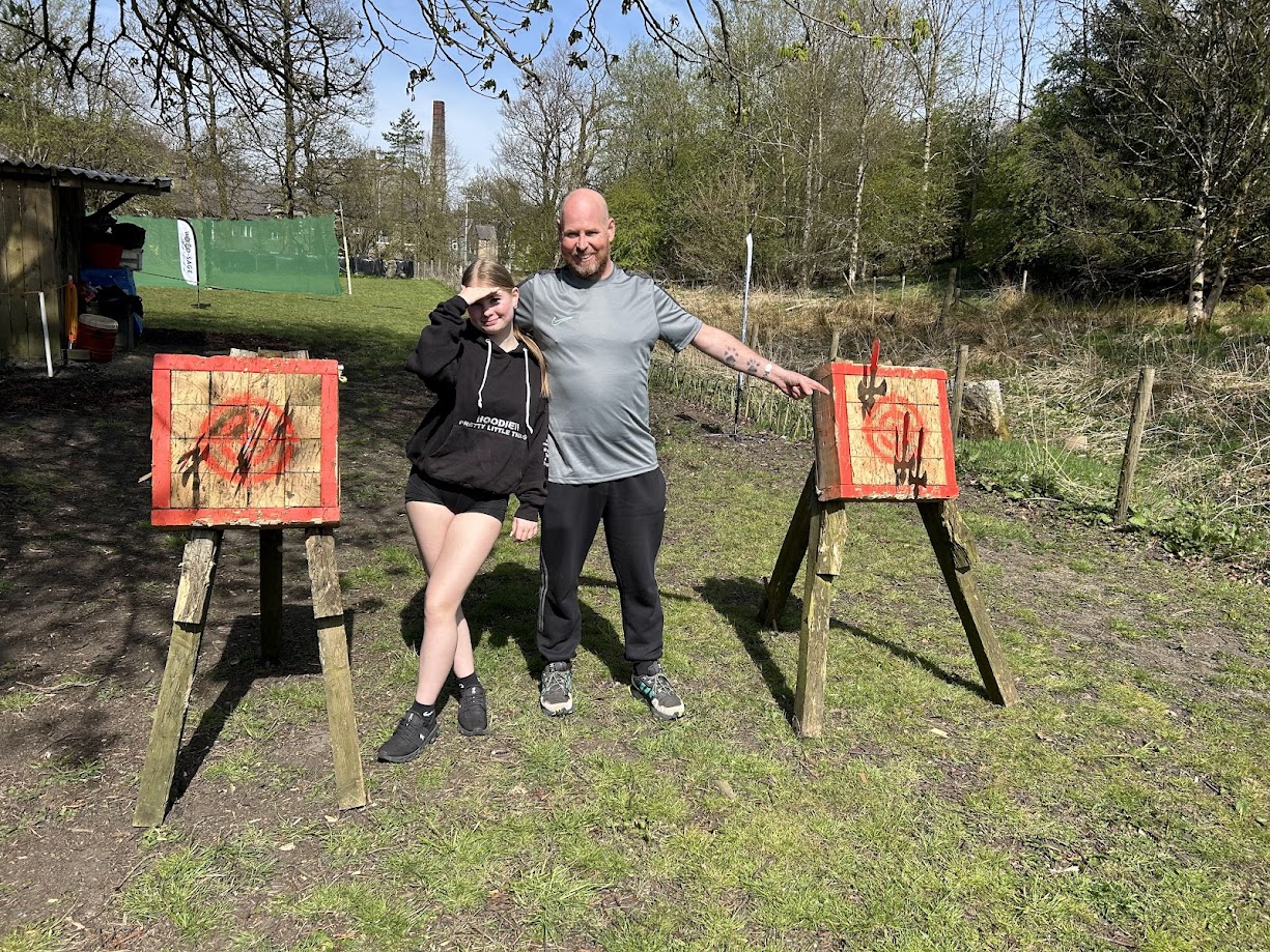 A Dad and daughter smiling on the tomahawk range at Wood-Sage Outdoor after a successful throw.