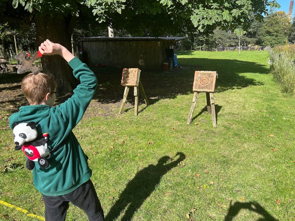 Outdoor mini axe throwing activity with wooden target boards.