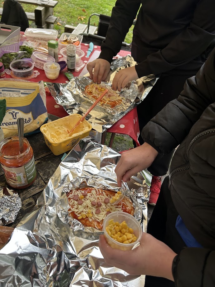Outdoor cooking activity: participants preparing pizzas for the fire.