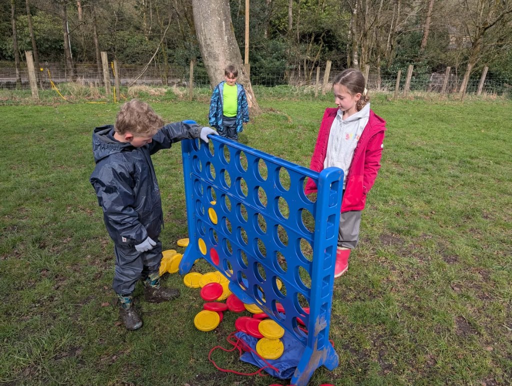 Children playing giant Connect Four outdoors during Easter HAF 2026 at Wood‑Sage Outdoor Education
